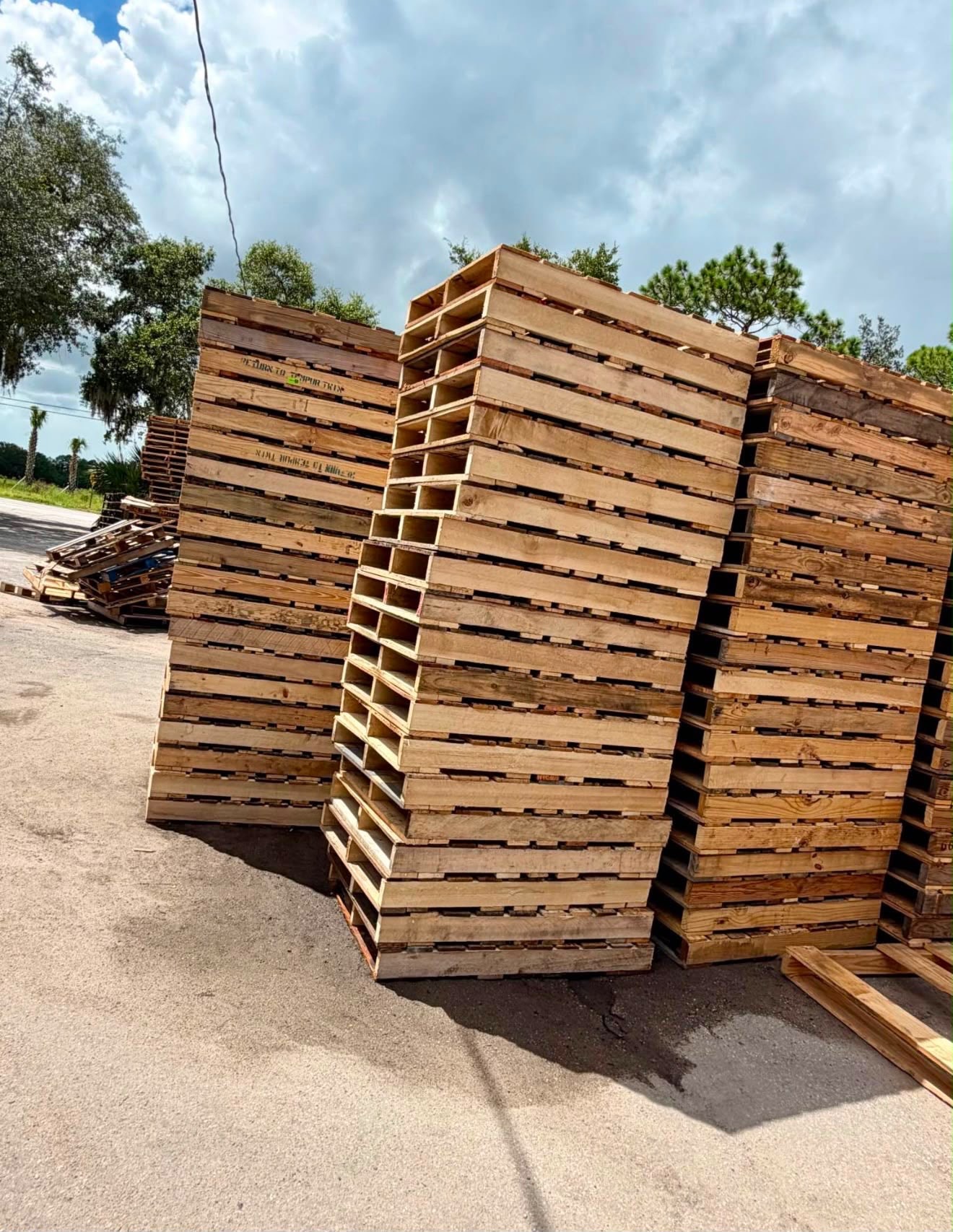 Wooden pallets stacked outdoors under blue sky